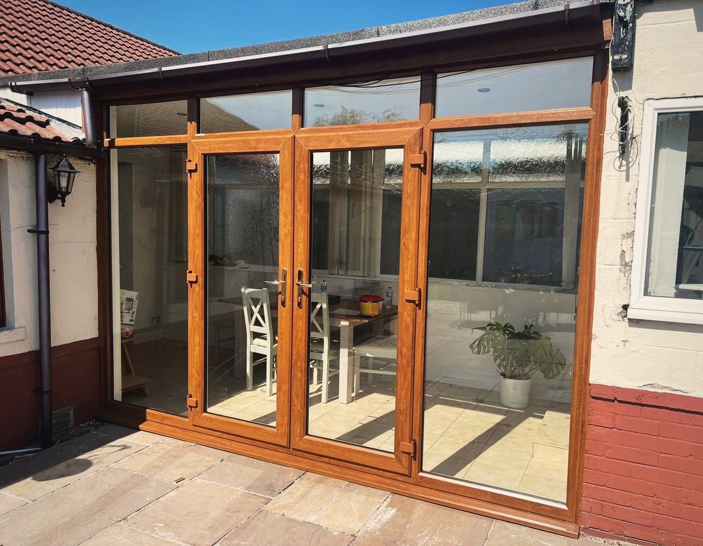 A pair of oak effect French doors with glazed side panels on the rear of a house