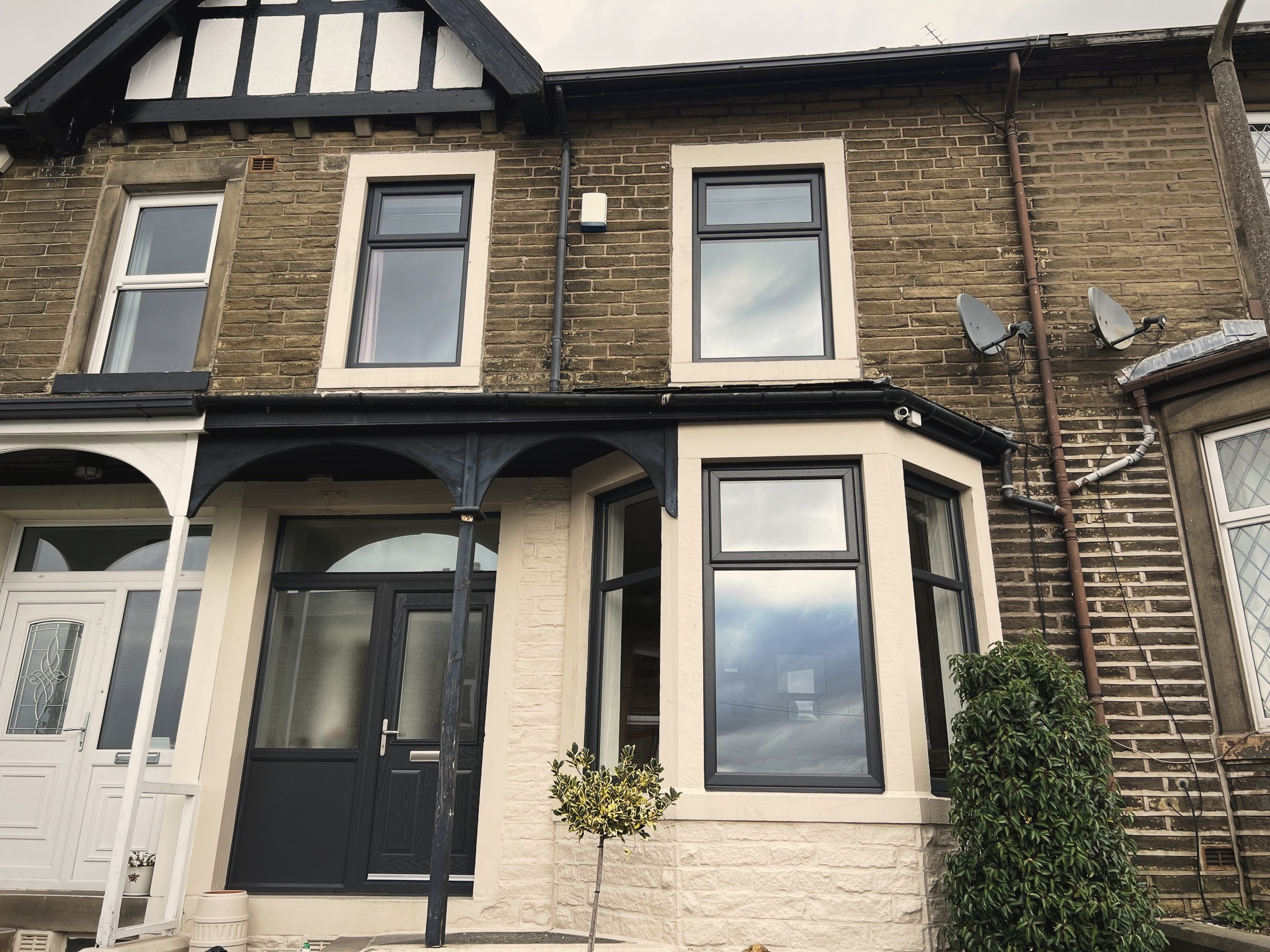 A gritstone terraced house in East Lancashire with new anthracite grey uPVC windows, a bay window and a composite front door
